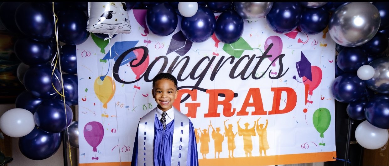 Navy and silver balloon arch around a Congrats Grad backdrop