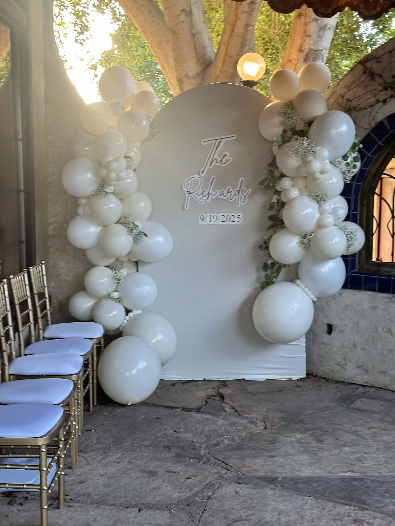 The Richards cream balloon ceremony arch with white roses and gold chiavari chairs